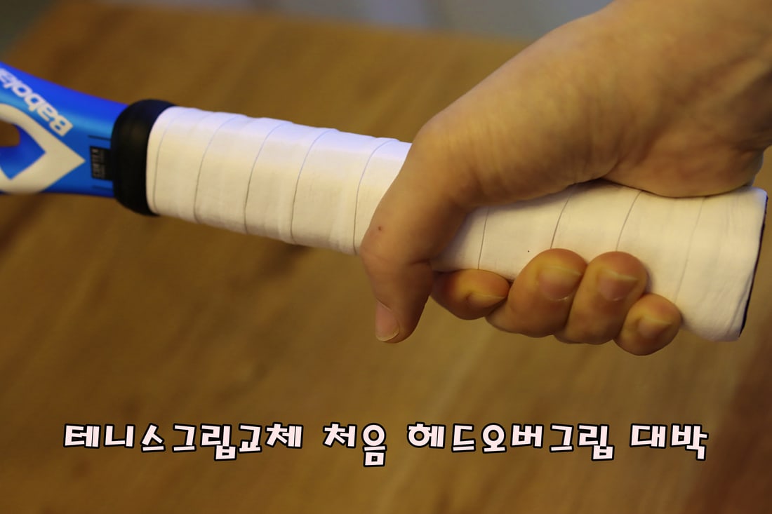 테니스 오버그립을 손잡이에 감는 손 — 약 절반씩 겹쳐 감는다